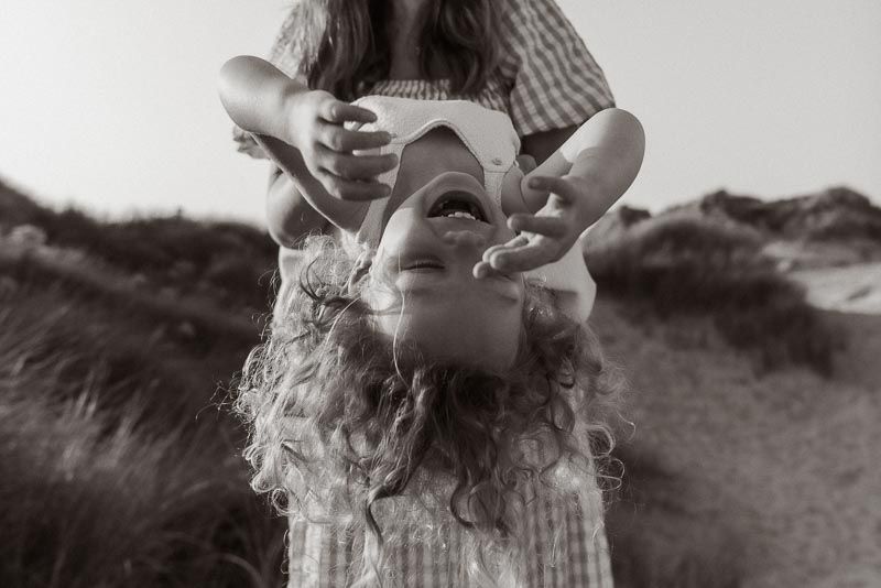 Black and white photo showing someone bending backwards with curly hair against a natural outdoor background.