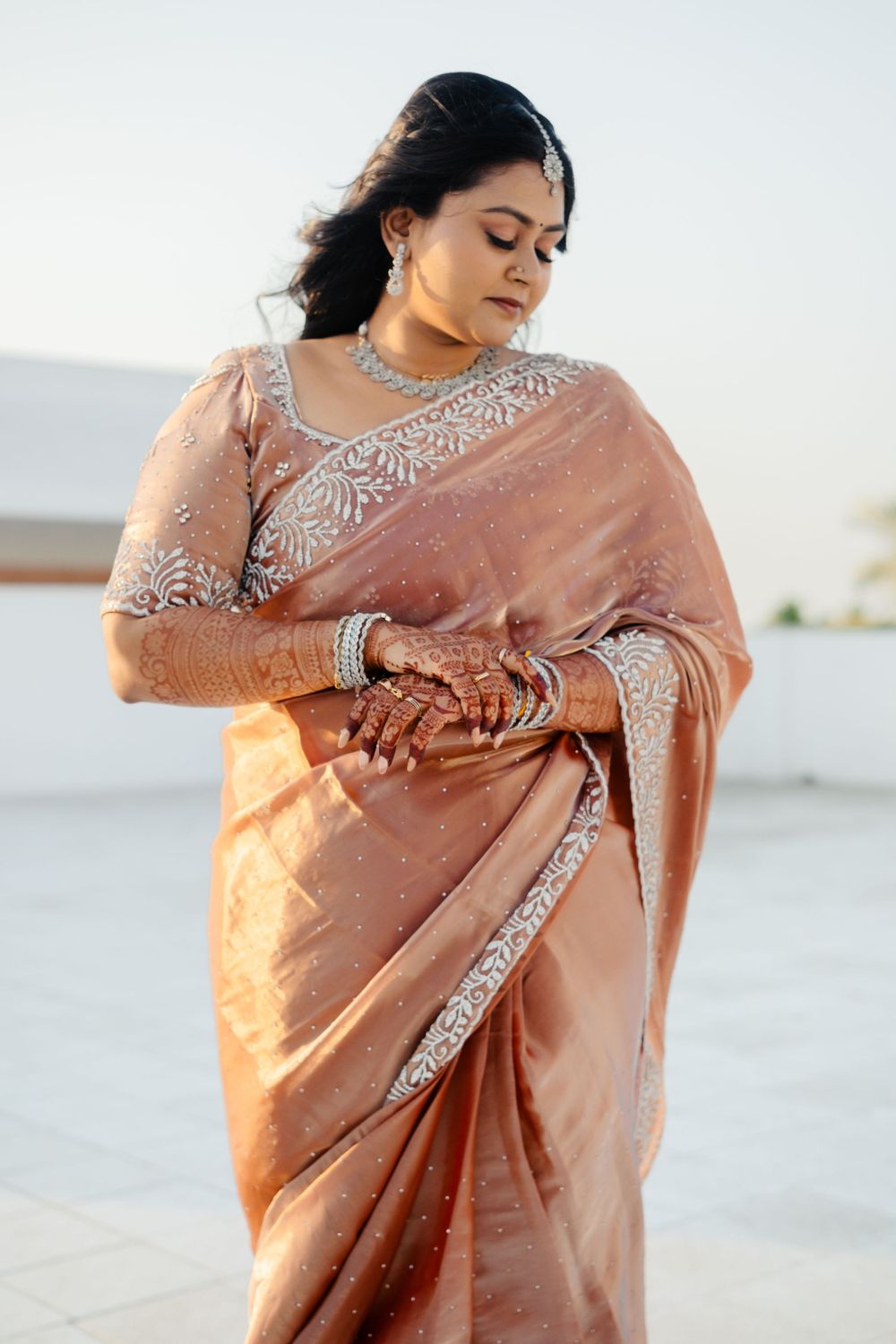 Beautiful peach-colored silk saree with intricate silver embroidery details and traditional Indian bridal jewelry.
