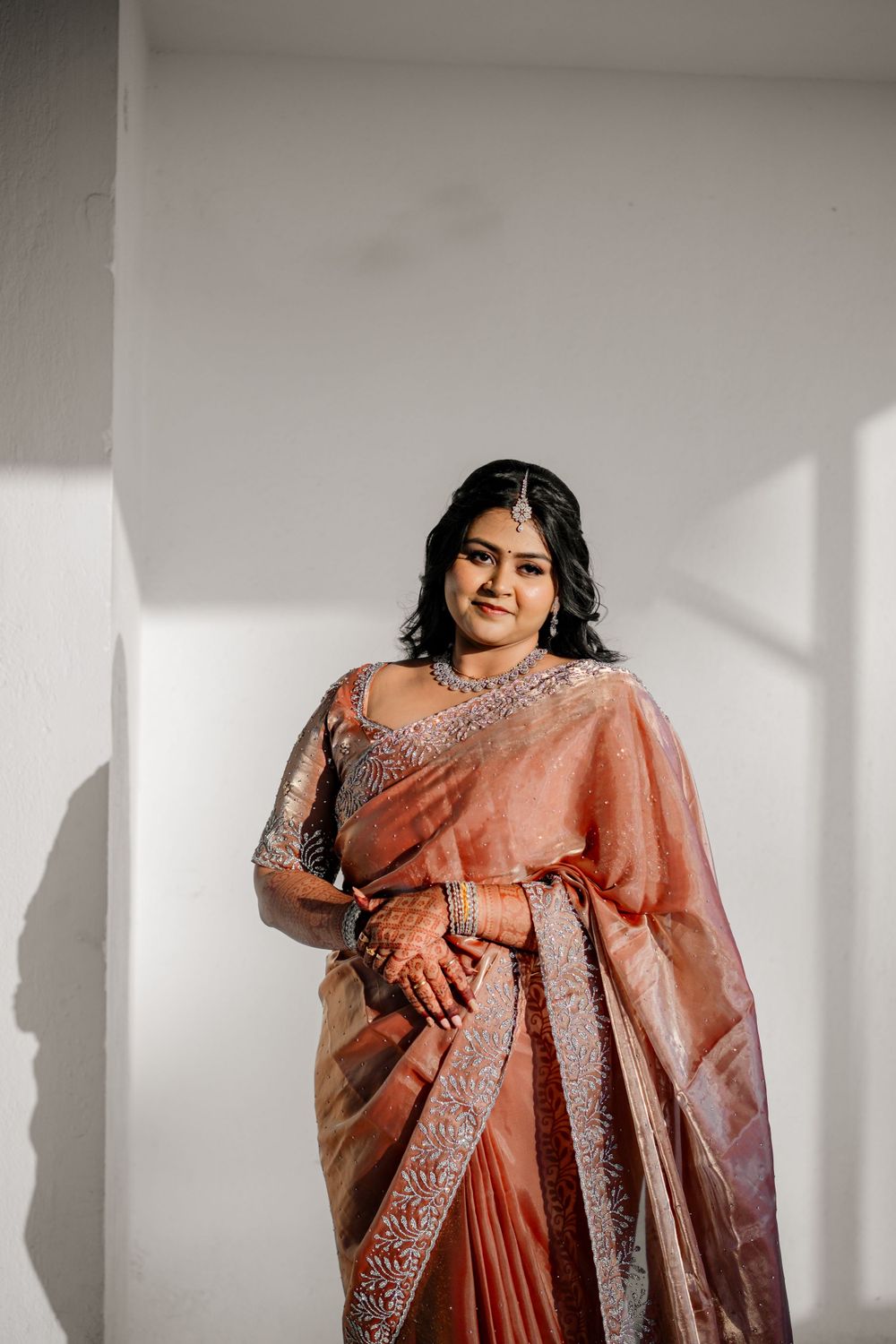 A detailed view of a peach-colored silk saree with intricate silver embroidery and embellishments.