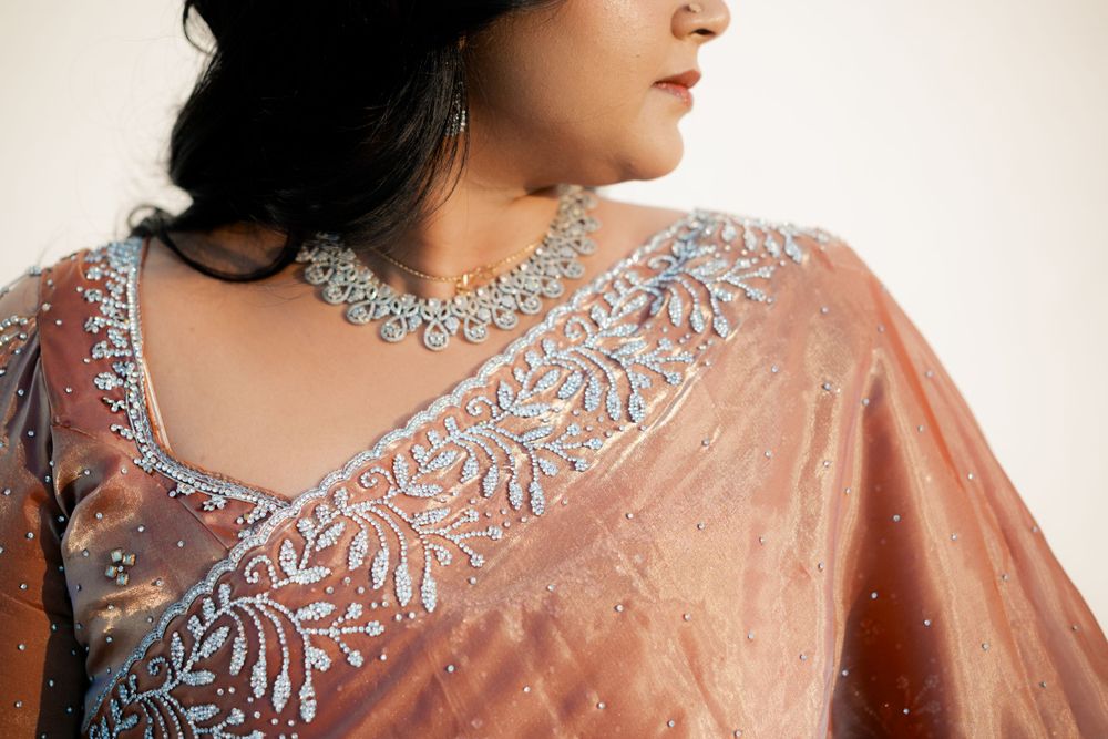 Close-up shot of an elegant peach saree with detailed silver embellishments and delicate neckline design.