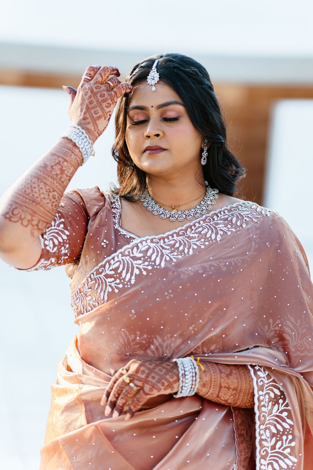 Close-up of intricate bridal mehndi designs and diamond jewelry with a peach-colored embroidered saree.
