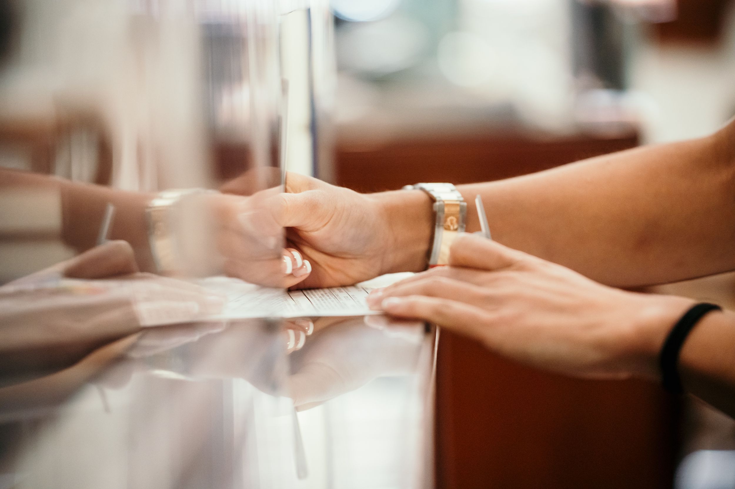 Hands exchanging rings in close up view through glass reflection at a jewelry counter.