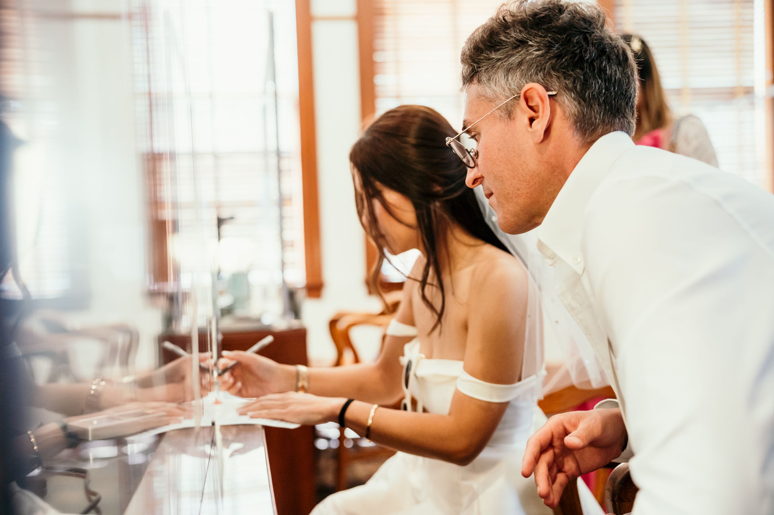 A couple celebrating their wedding day share an intimate moment while looking at a table together during a reception.
