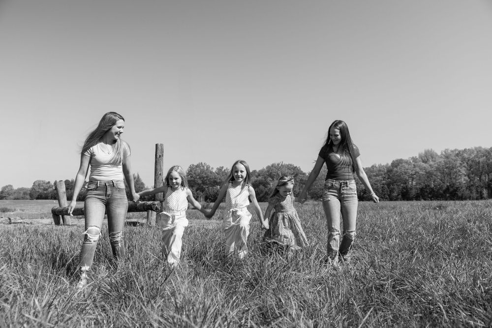 Group of young people walking together across a sunny field in black and white photography.