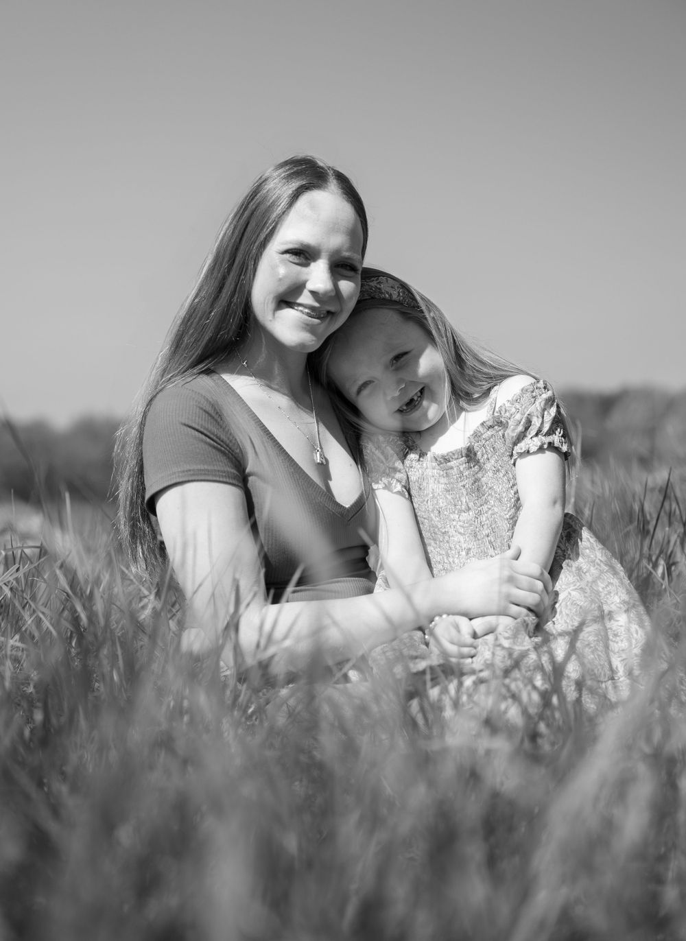 A tender black and white portrait of an embrace in a meadow showing a sweet candid moment between two people.