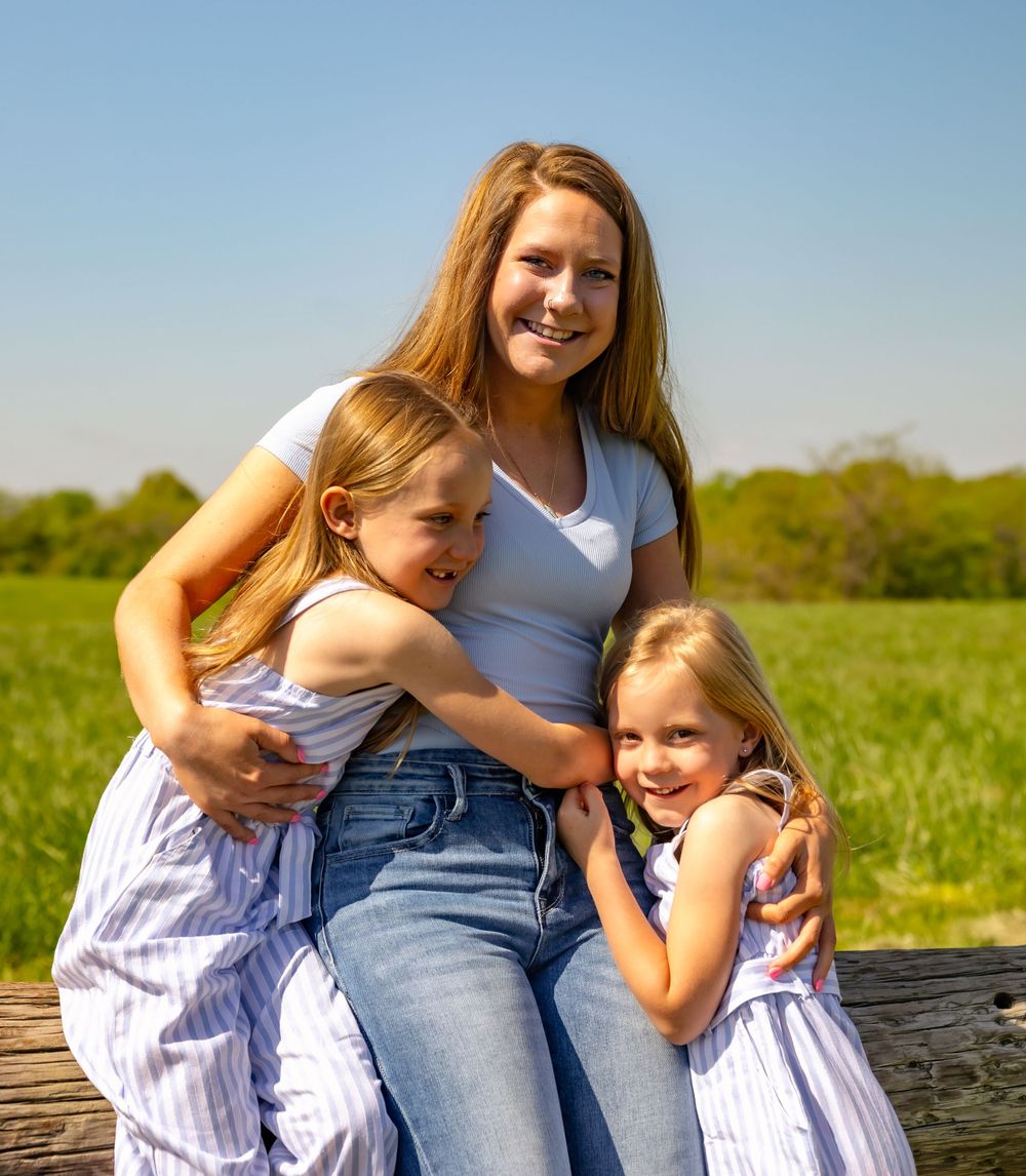 Family shares joyful laughter while sitting together outdoors in a grassy field on a bright summer day.