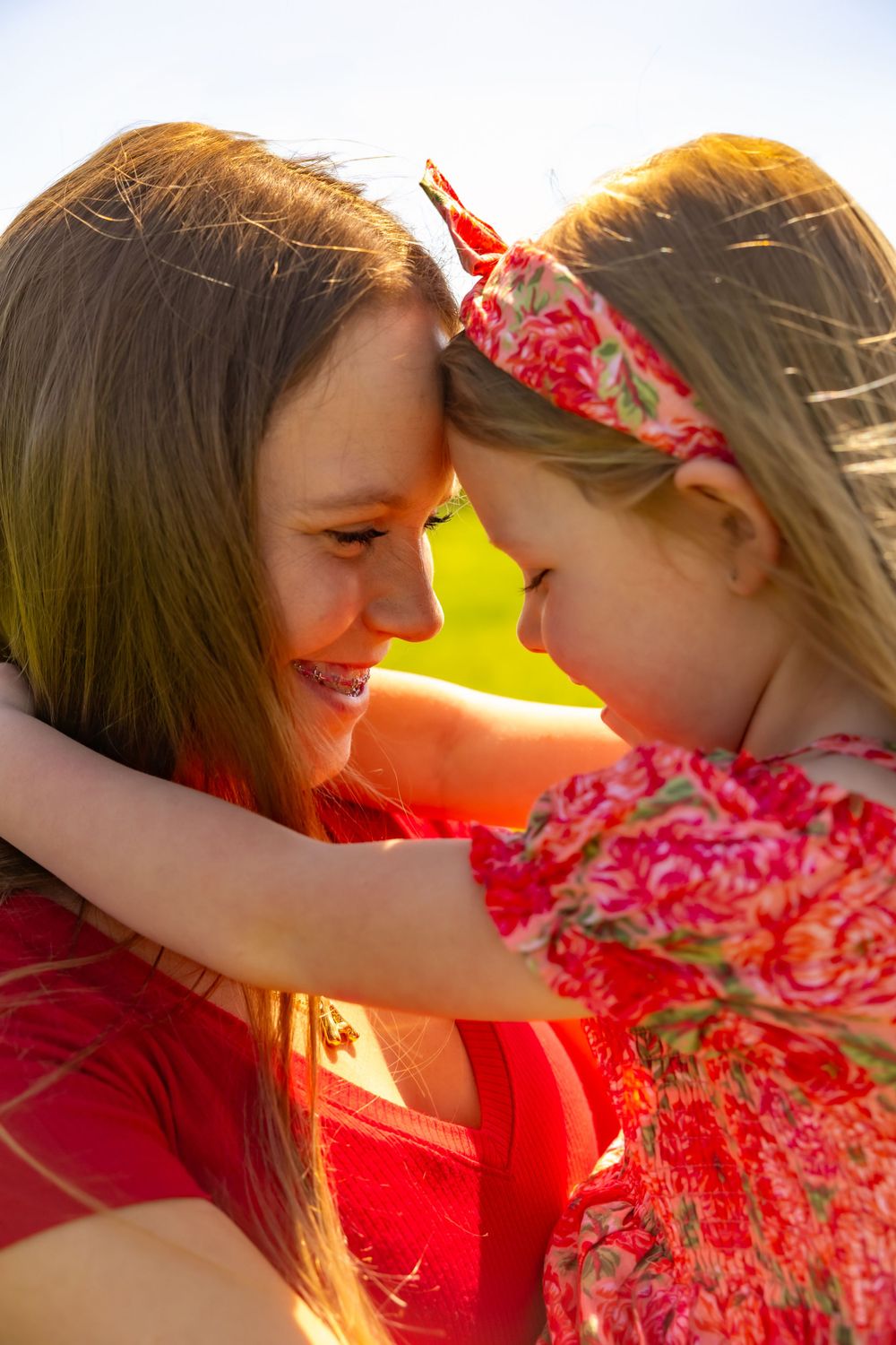 A joyful embrace between parent and child sharing a close moment in golden sunlight with floral accents.