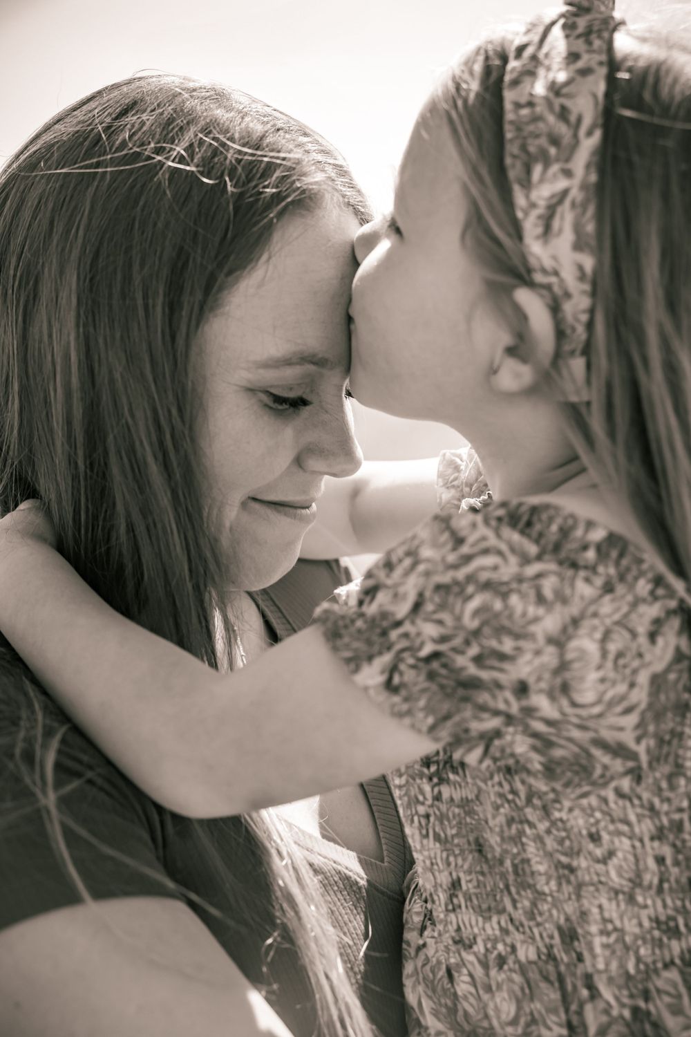 A tender black and white portrait shows two people sharing an intimate moment with heads close together.