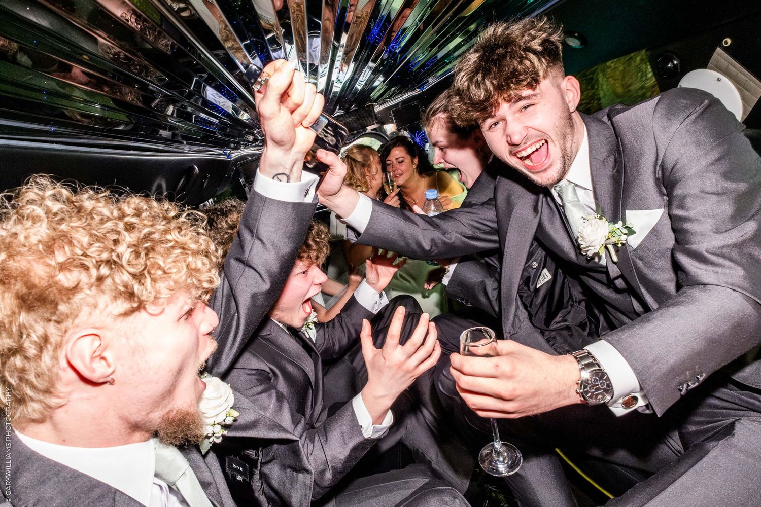 Young people in formal suits celebrating with champagne glasses during a party with dynamic lighting effects.