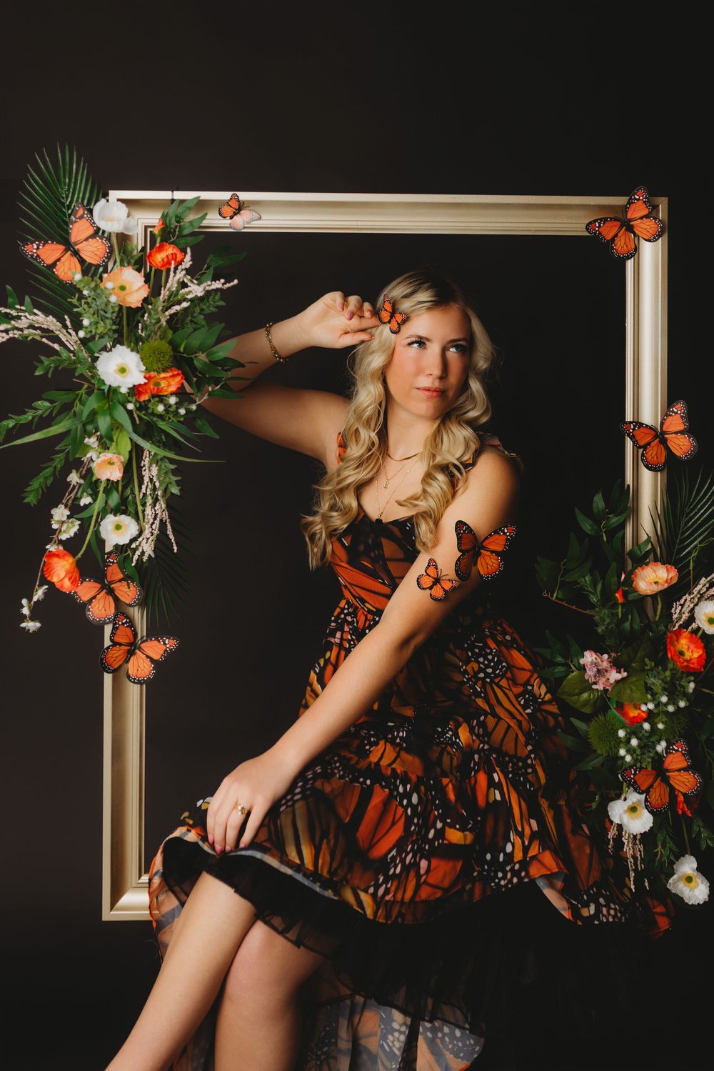 Elegant butterfly-themed photoshoot setup with white frame and orange floral accents.