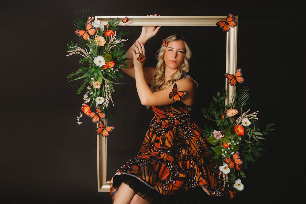 Dreamy portrait featuring monarch butterfly dress and decorative frame with flowers.