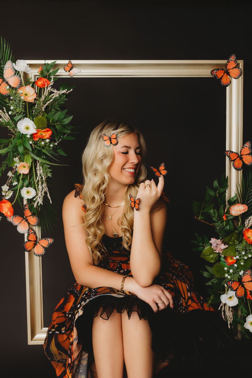 Romantic portrait with orange monarch butterflies and white flowers on dark backdrop.