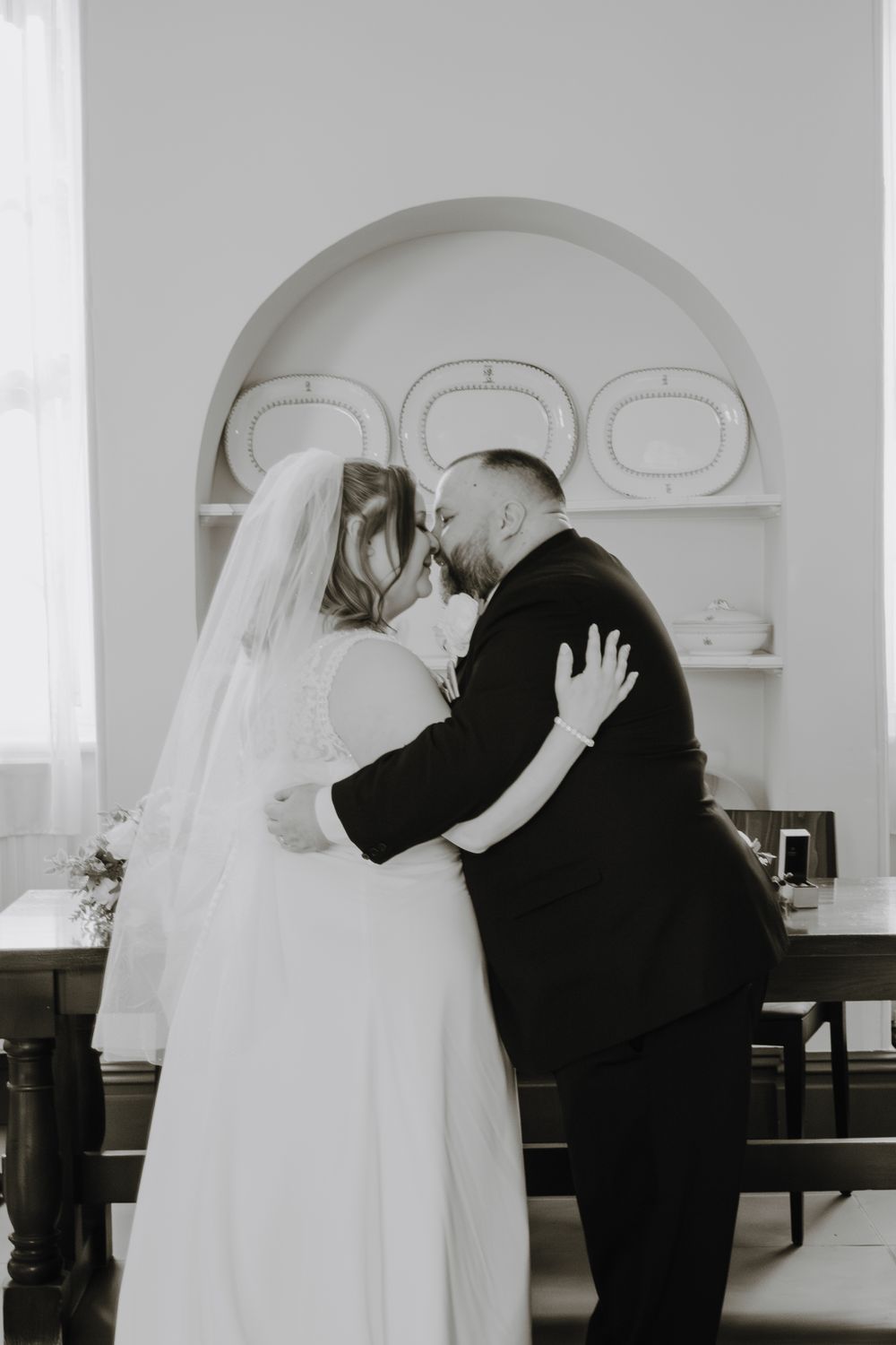 A tender moment shared between a couple during their wedding ceremony, captured in black and white.