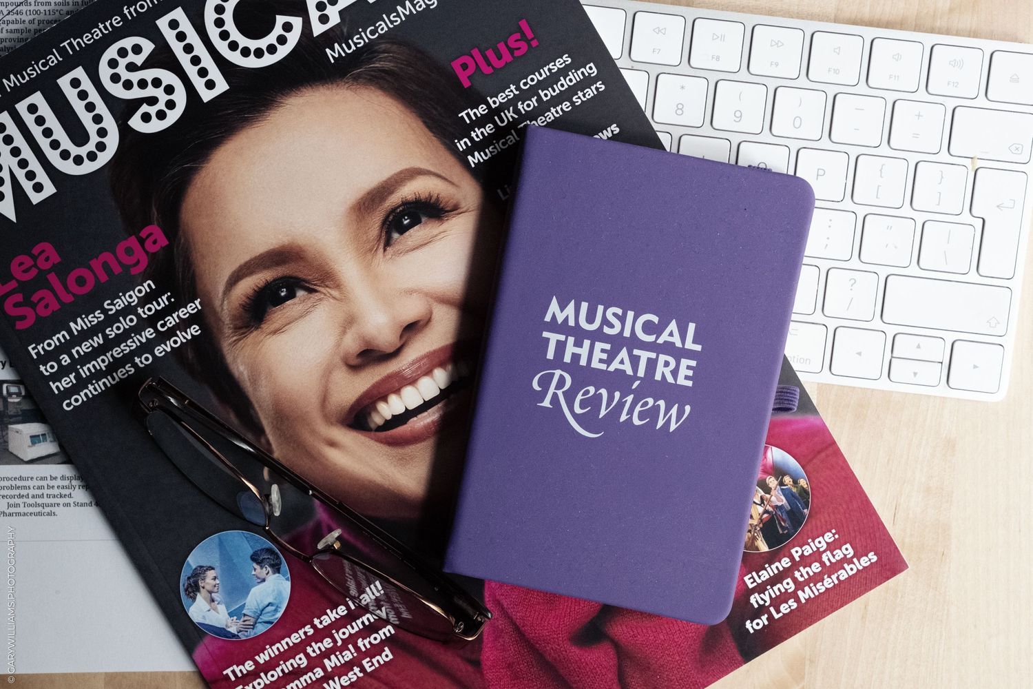 Theater magazines including Musical Theatre Review displayed on white keyboard.