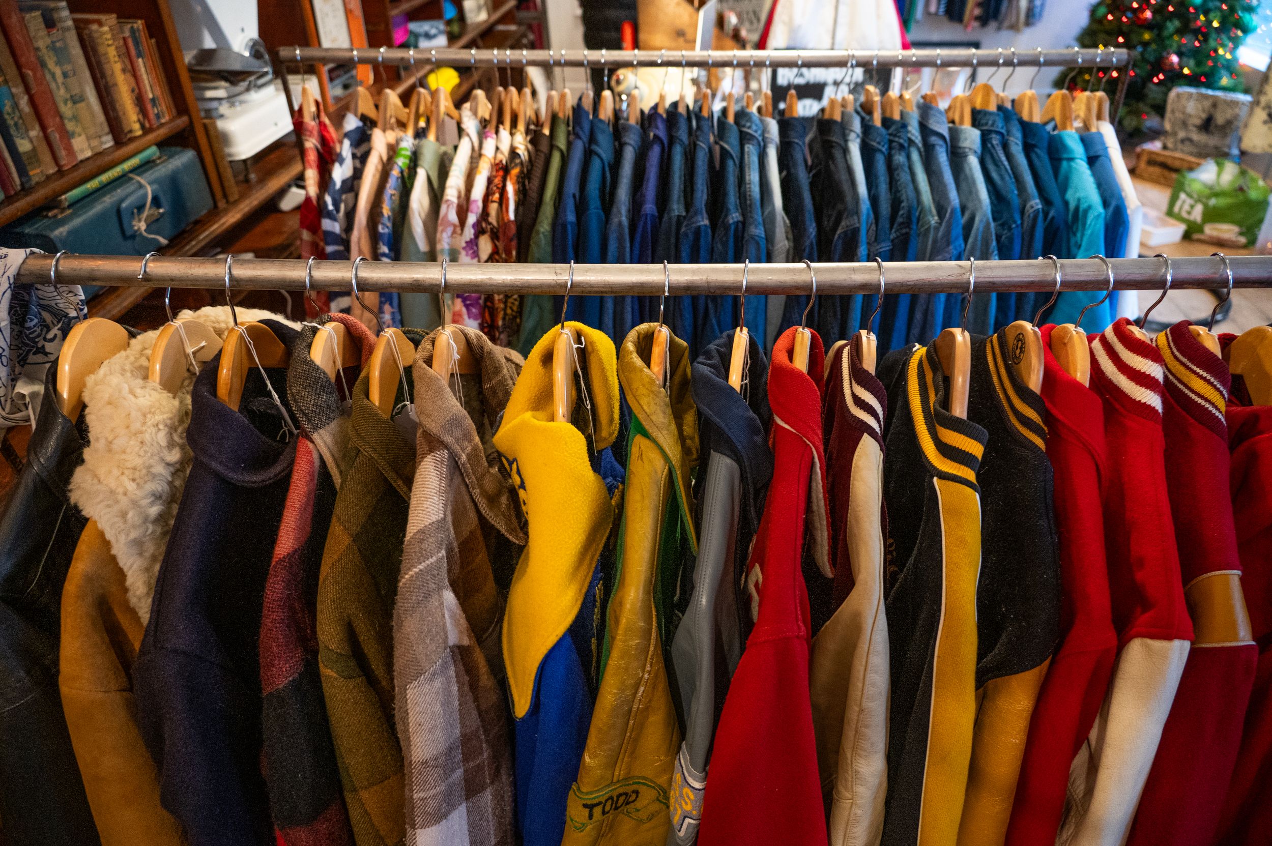 Colorful vintage clothing hanging on racks in a thrift store, featuring yellow, blue, and red garments.