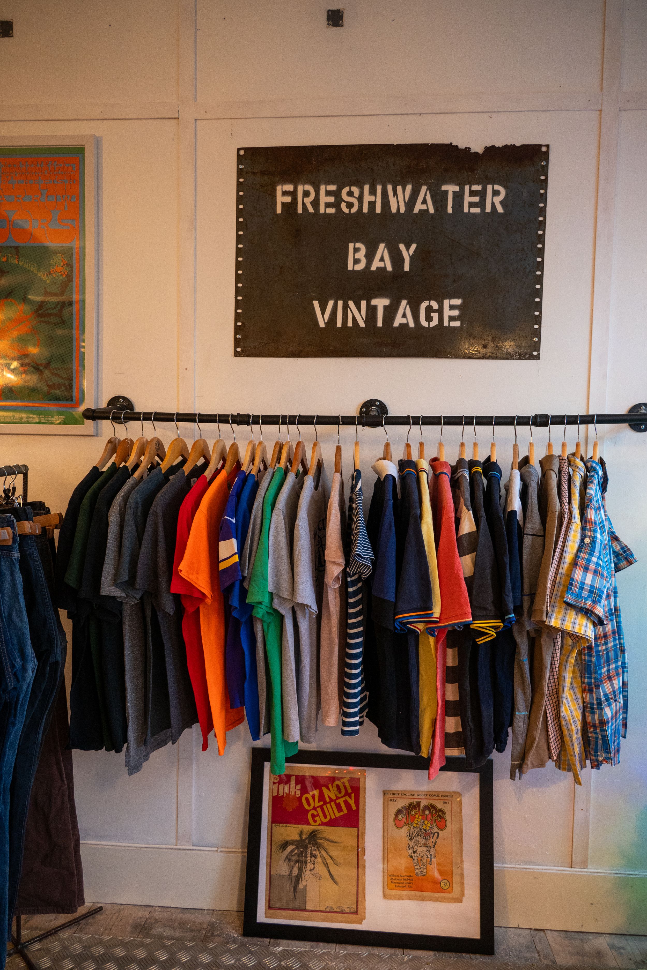 A rack of colorful vintage clothing displayed under a 'Freshwater Bay Vintage' sign in a retail store.