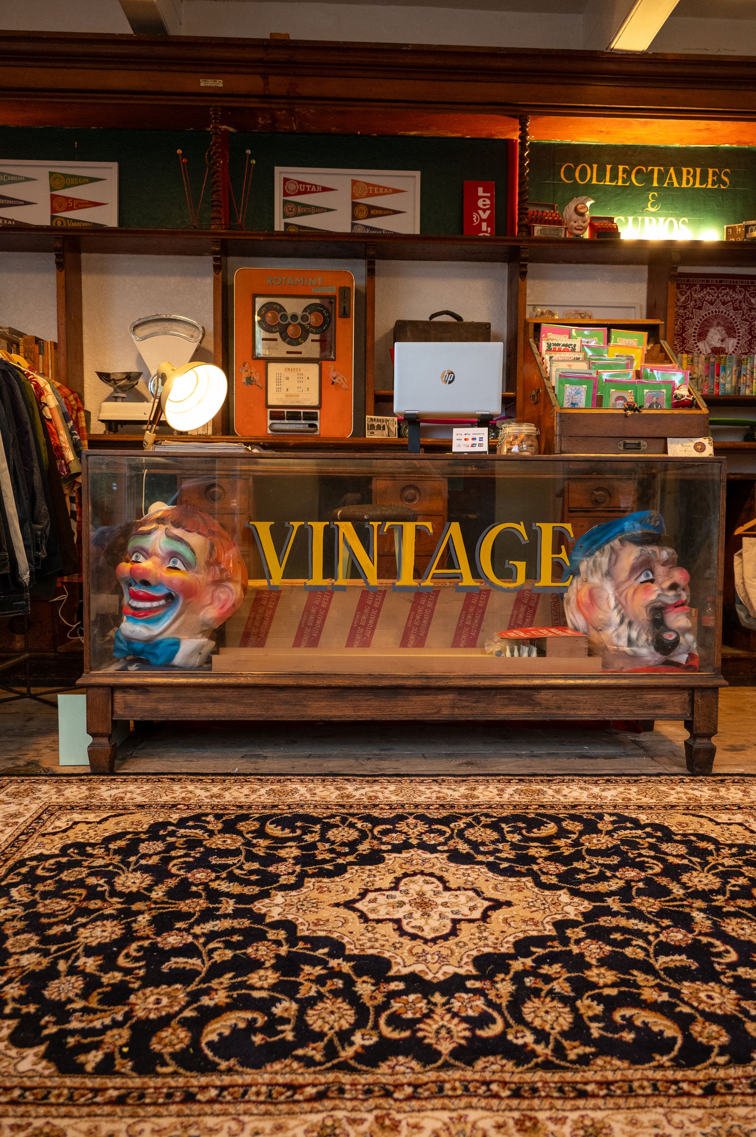 A vintage furniture display with a wooden cabinet, decorative collectables, and a patterned oriental rug on the floor.