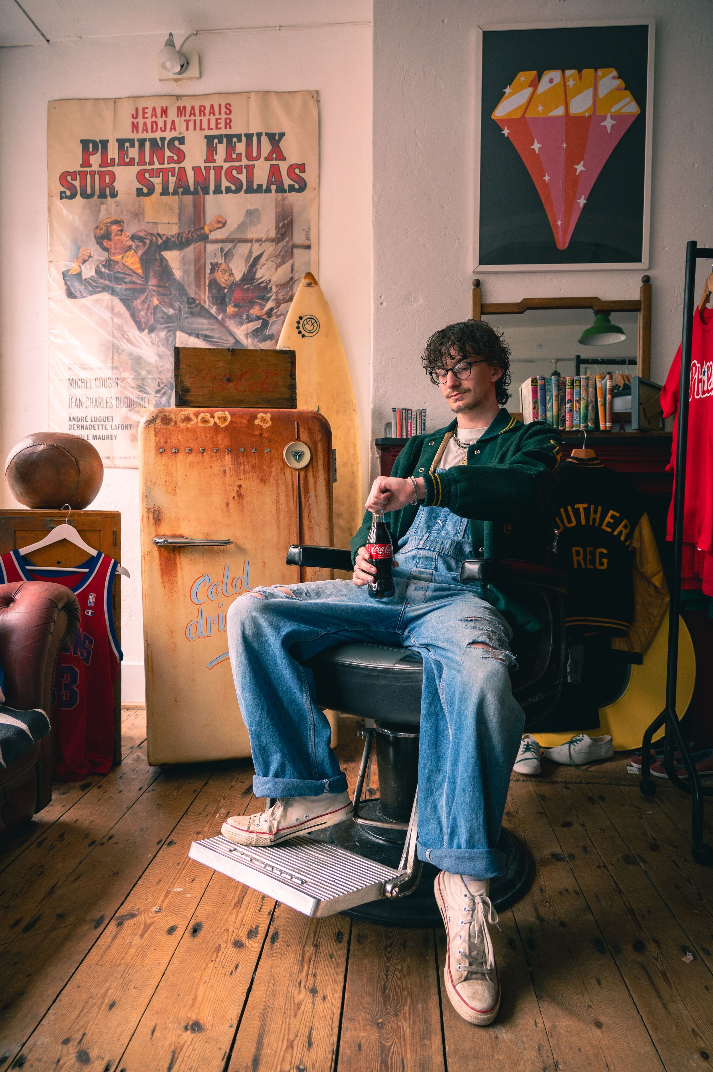 Retro room interior with vintage movie poster, wooden floor, and person sitting in casual 70s style with blue jeans.