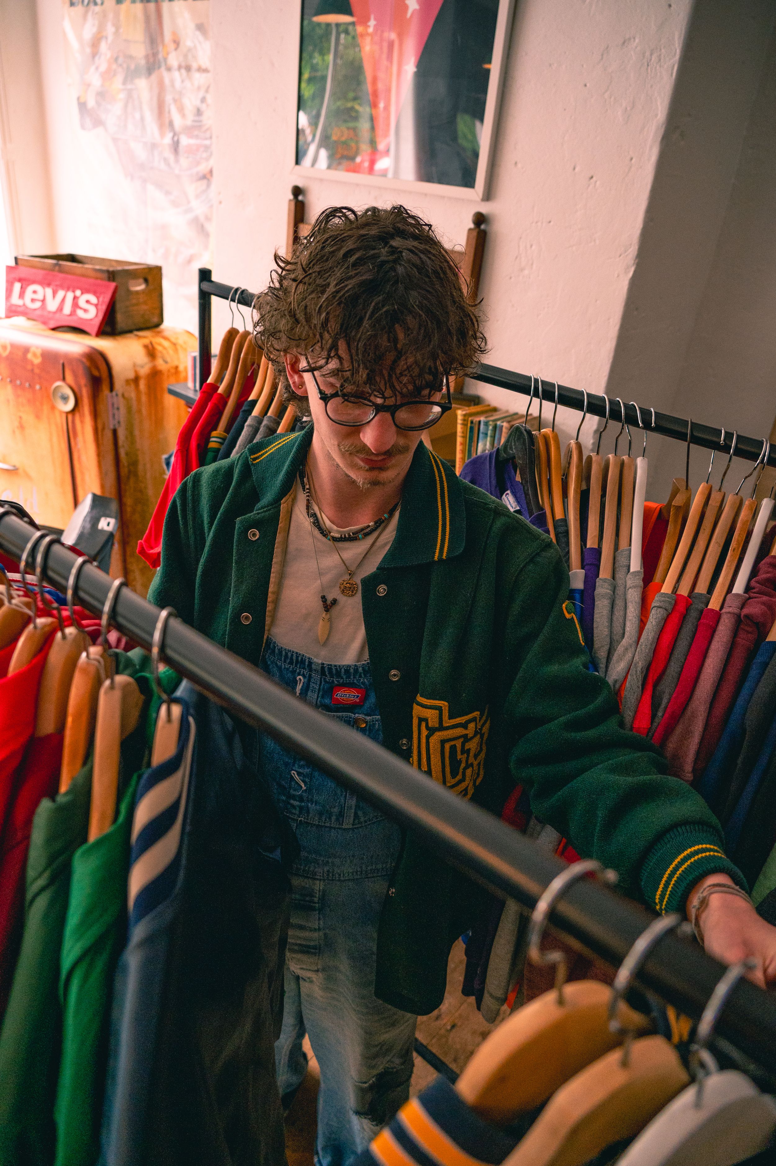 A vintage clothing store interior with racks of colorful garments and a Levi's sign visible in the background.