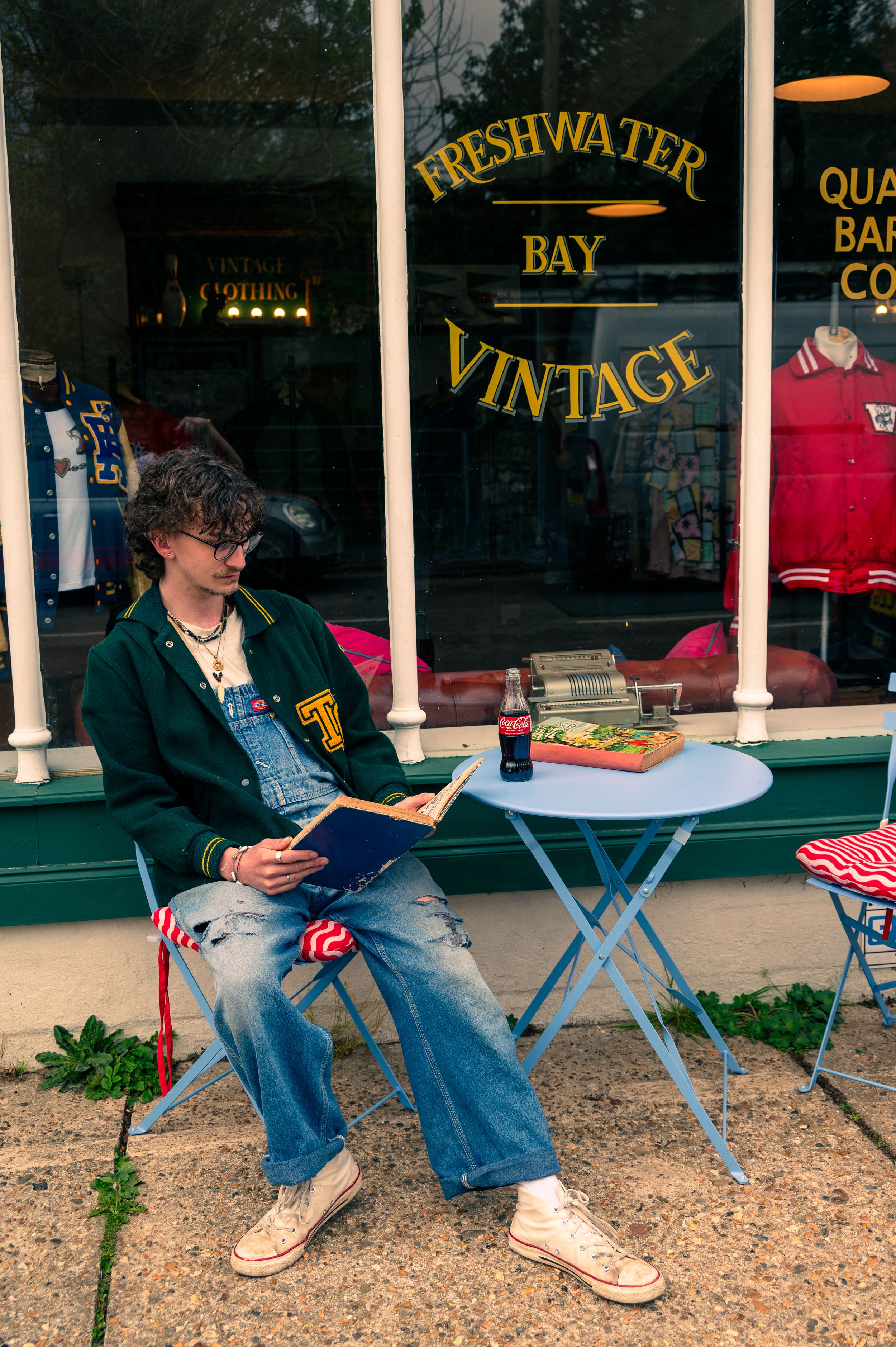 A vintage clothing storefront with outdoor seating and retro signage displayed in the window.