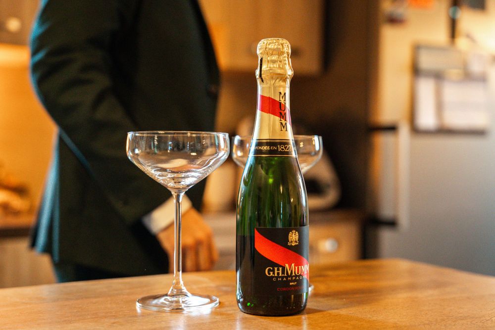 Champagne bottle and coupe glasses on wooden table during wedding celebration.