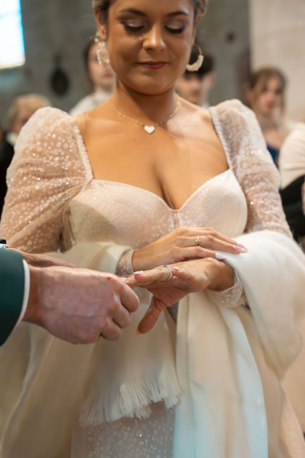 Close-up of a wedding ring exchange ceremony with lace sleeves and delicate jewelry details.
