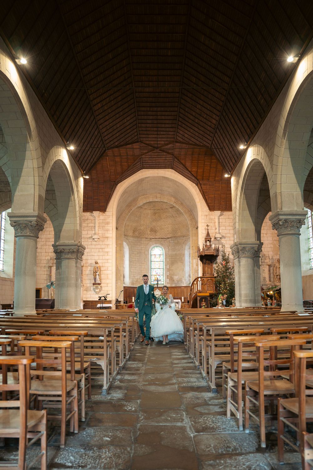 Wedding ceremony in historic stone church with vaulted ceiling and wooden pews.