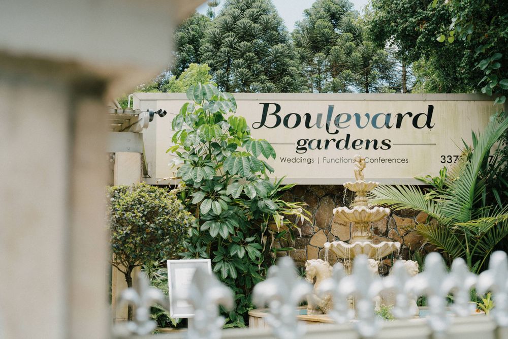 A sign reading 'Boulevard gardens' nestled among lush greenery and white garden features in an outdoor setting.