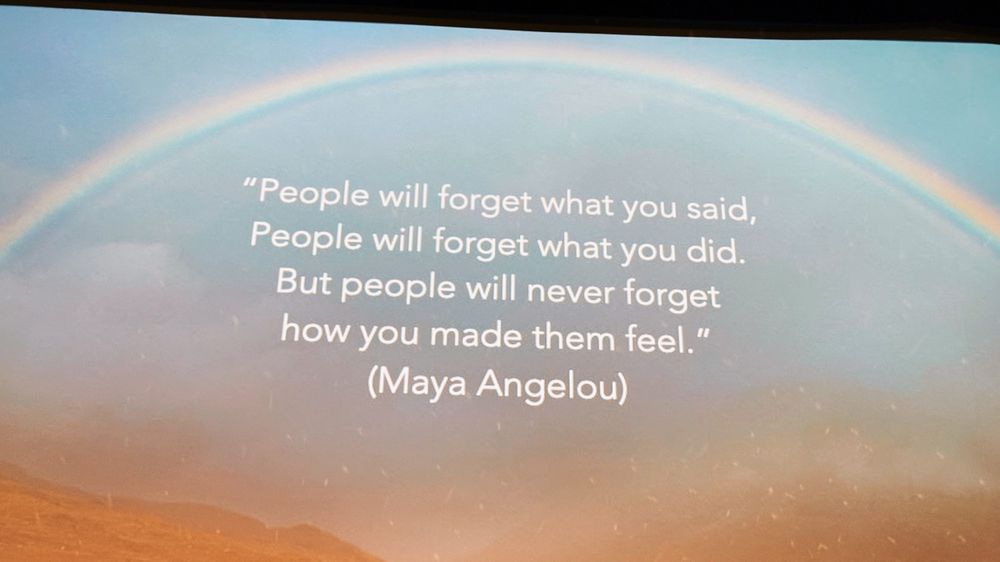 Maya Angelou quote about making people feel appears on screen over sunset sky with rainbow.