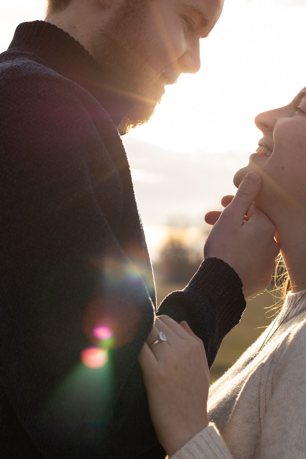 Intimate couple's portrait with golden sunset backlighting creating lens flares.