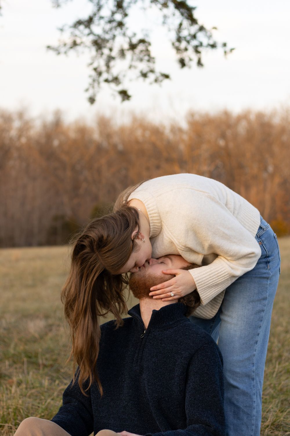 Two people sharing an intimate moment in a field with warm autumn colors.