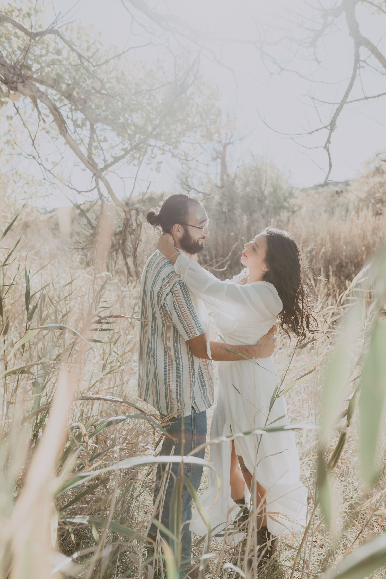 Couple embracing romantically among tall golden grasses in nature.