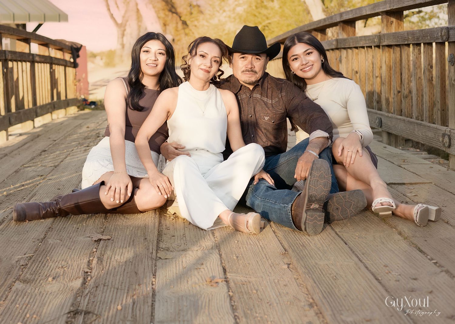 Group poses together on wooden deck during sunset photoshoot with warm lighting and rustic backdrop.