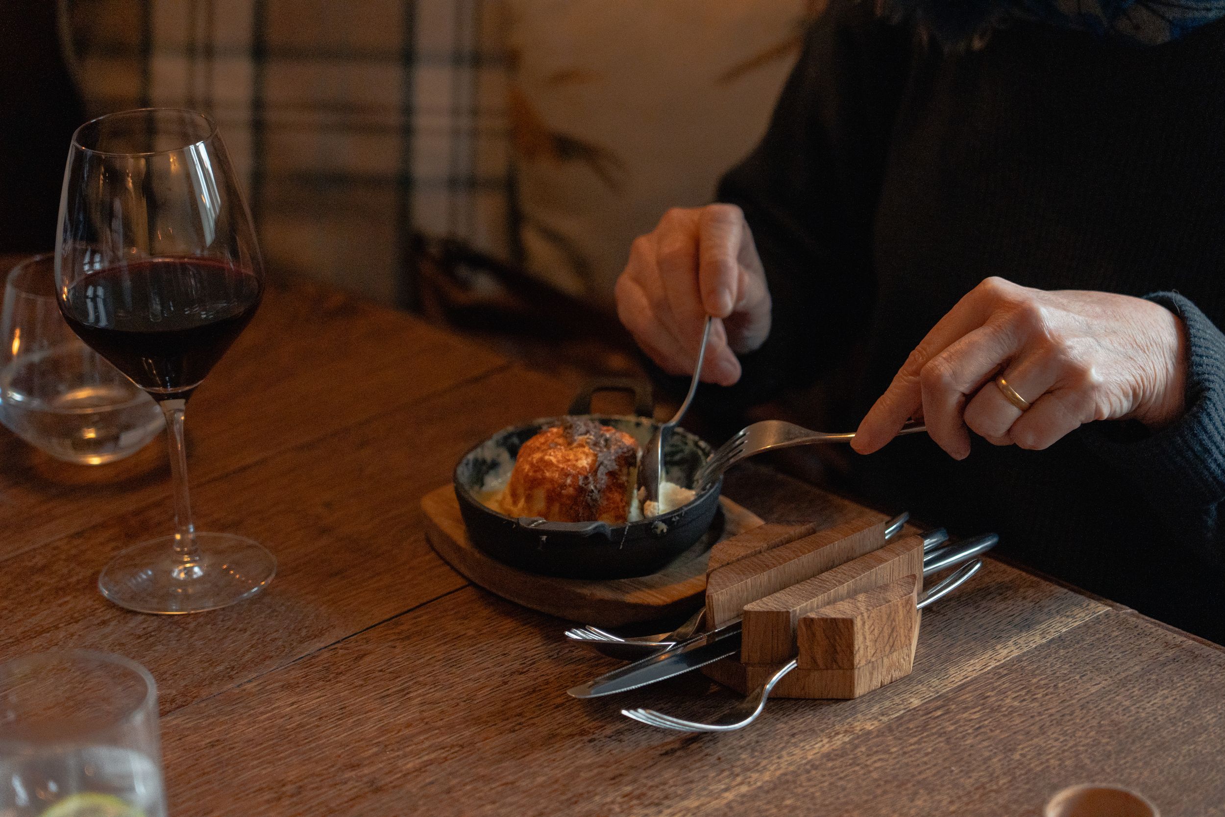 Close-up of drinks and dining settings on a dark wooden restaurant table.