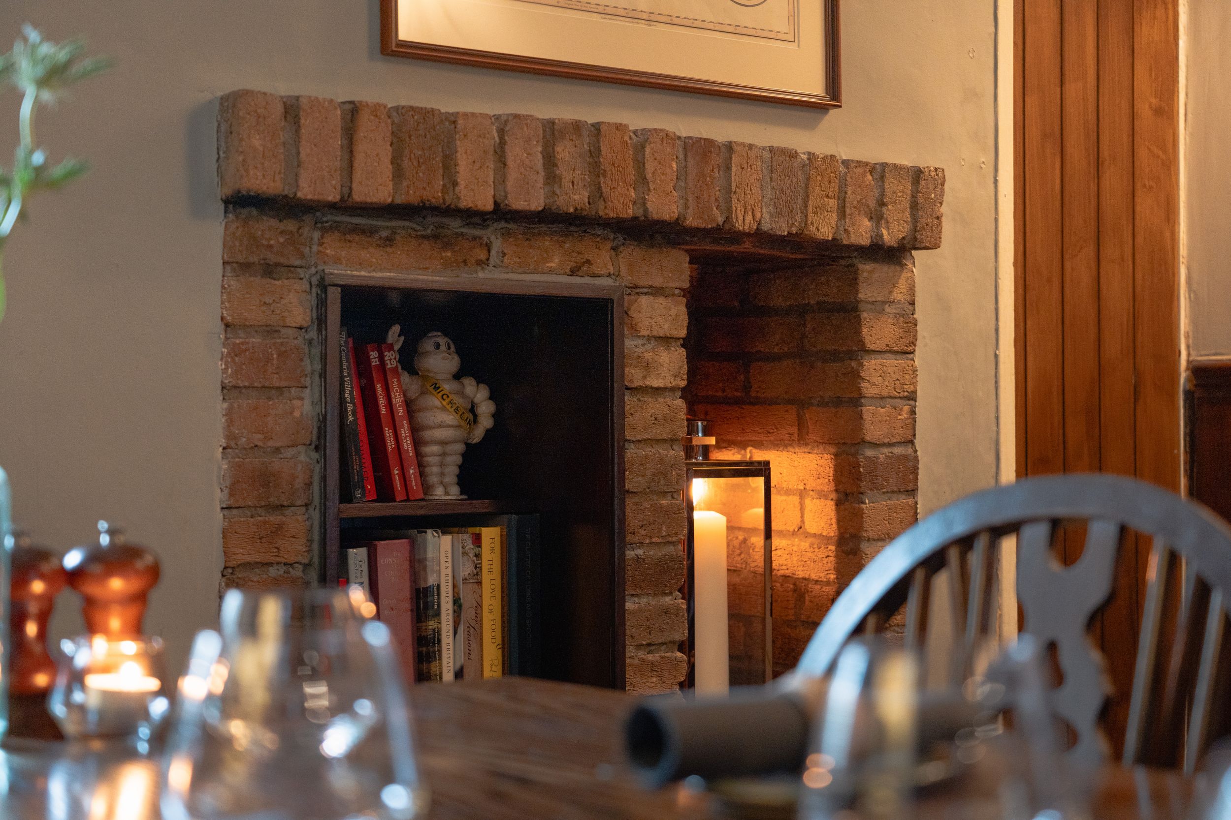 A brick fireplace and wooden interior create a warm, rustic dining atmosphere.
