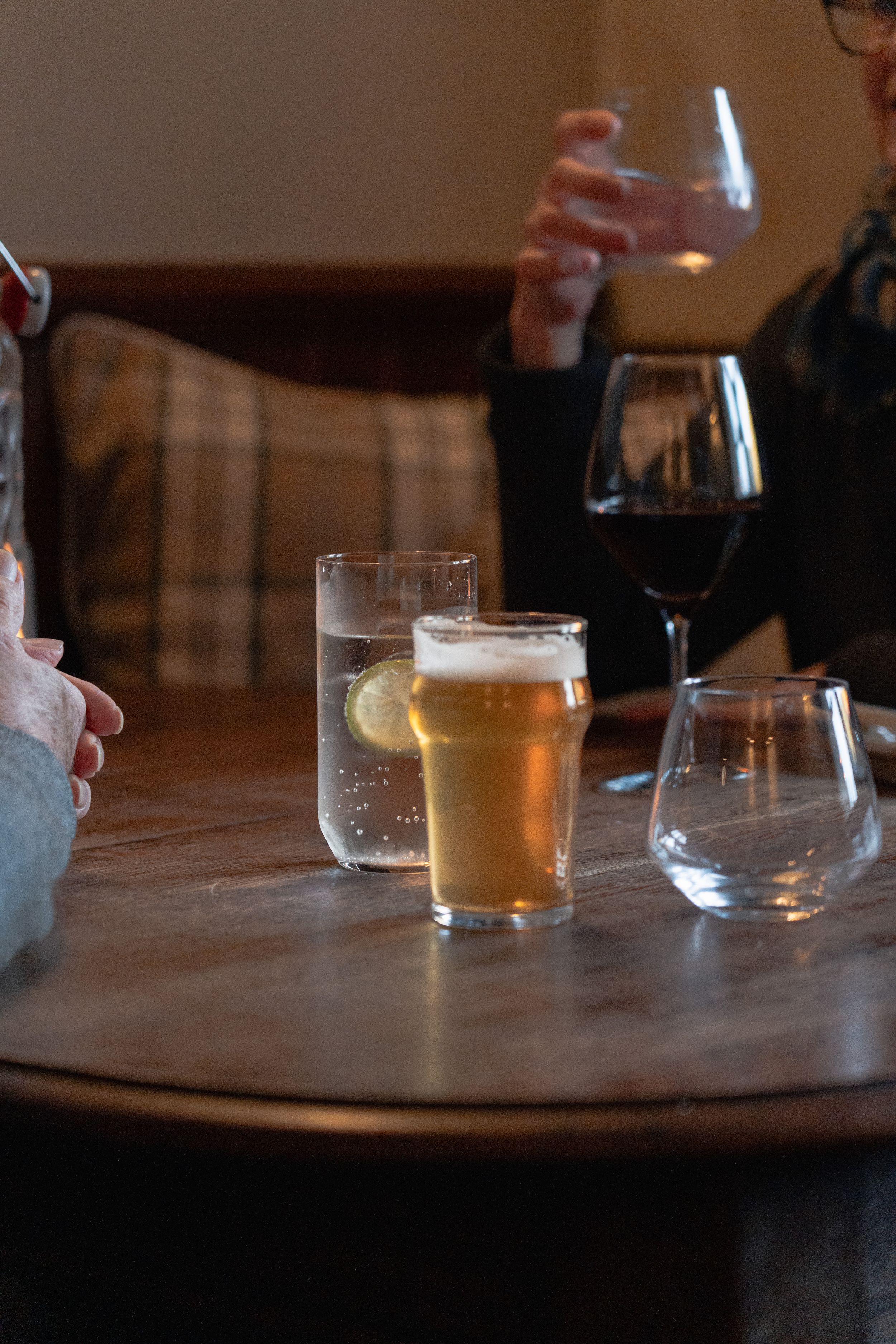 Beer glasses and drinks sit on a wooden table in dim restaurant lighting.
