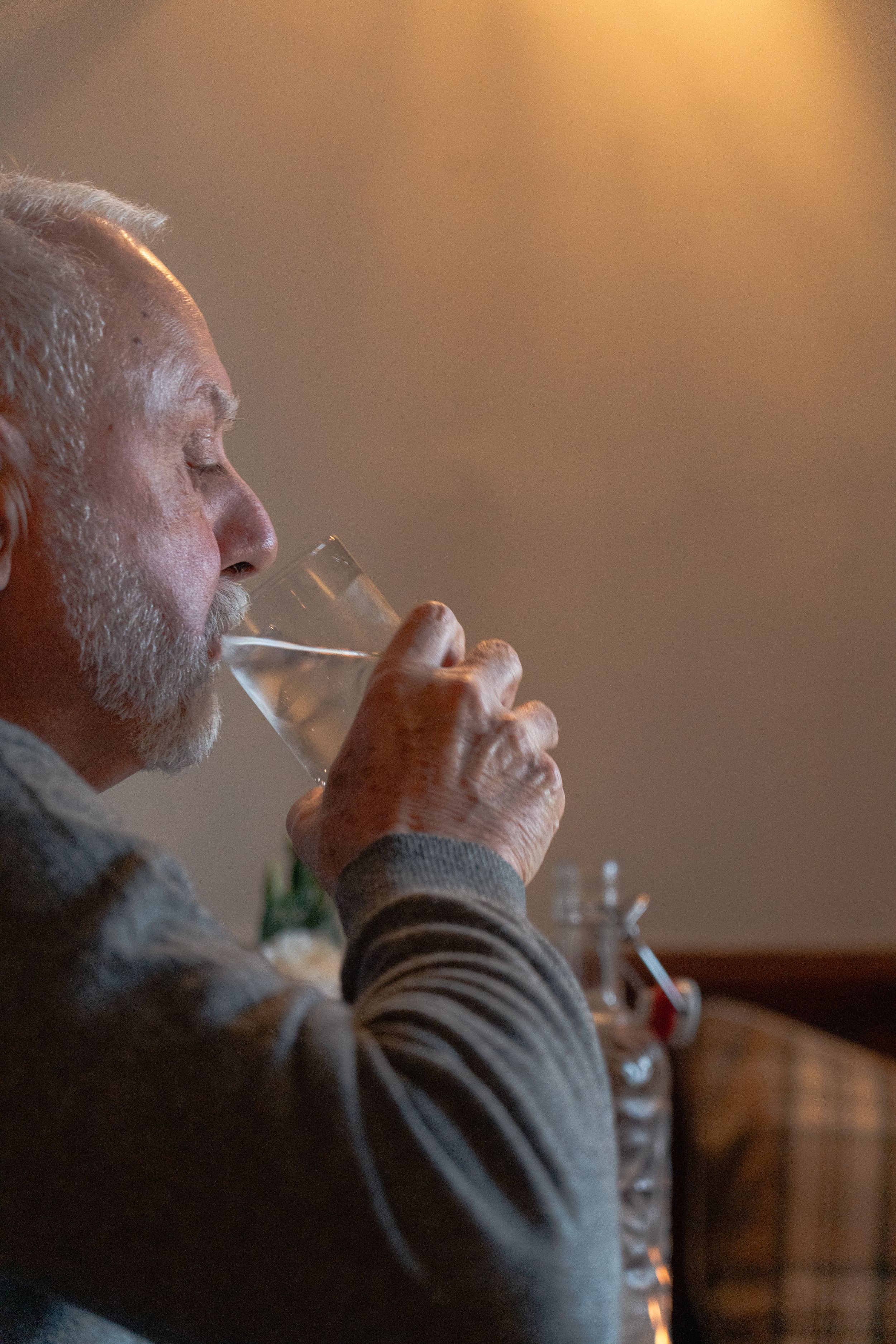 Someone sips from a glass in warm ambient lighting at a restaurant.