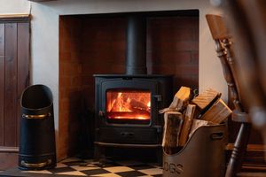 Black wood stove sits against a white wall in a cozy restaurant corner.