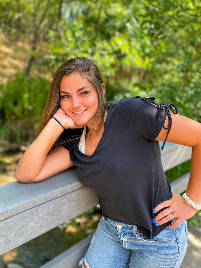 girl leaning on wooden fence smiling