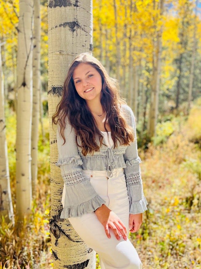 girl leaning against a tree