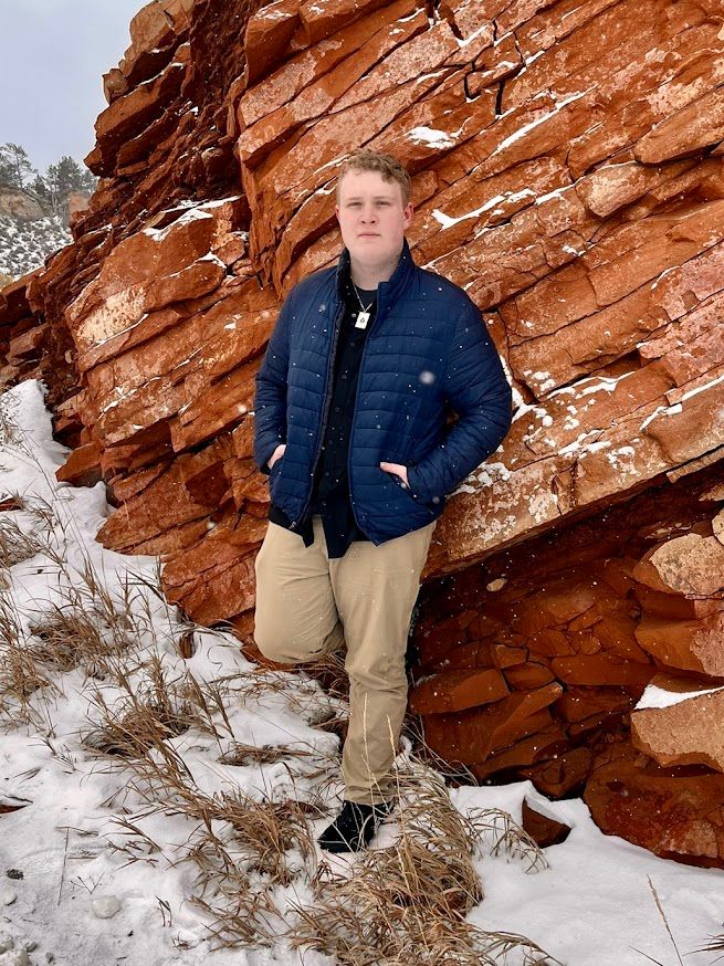 man standing up against a rock wall