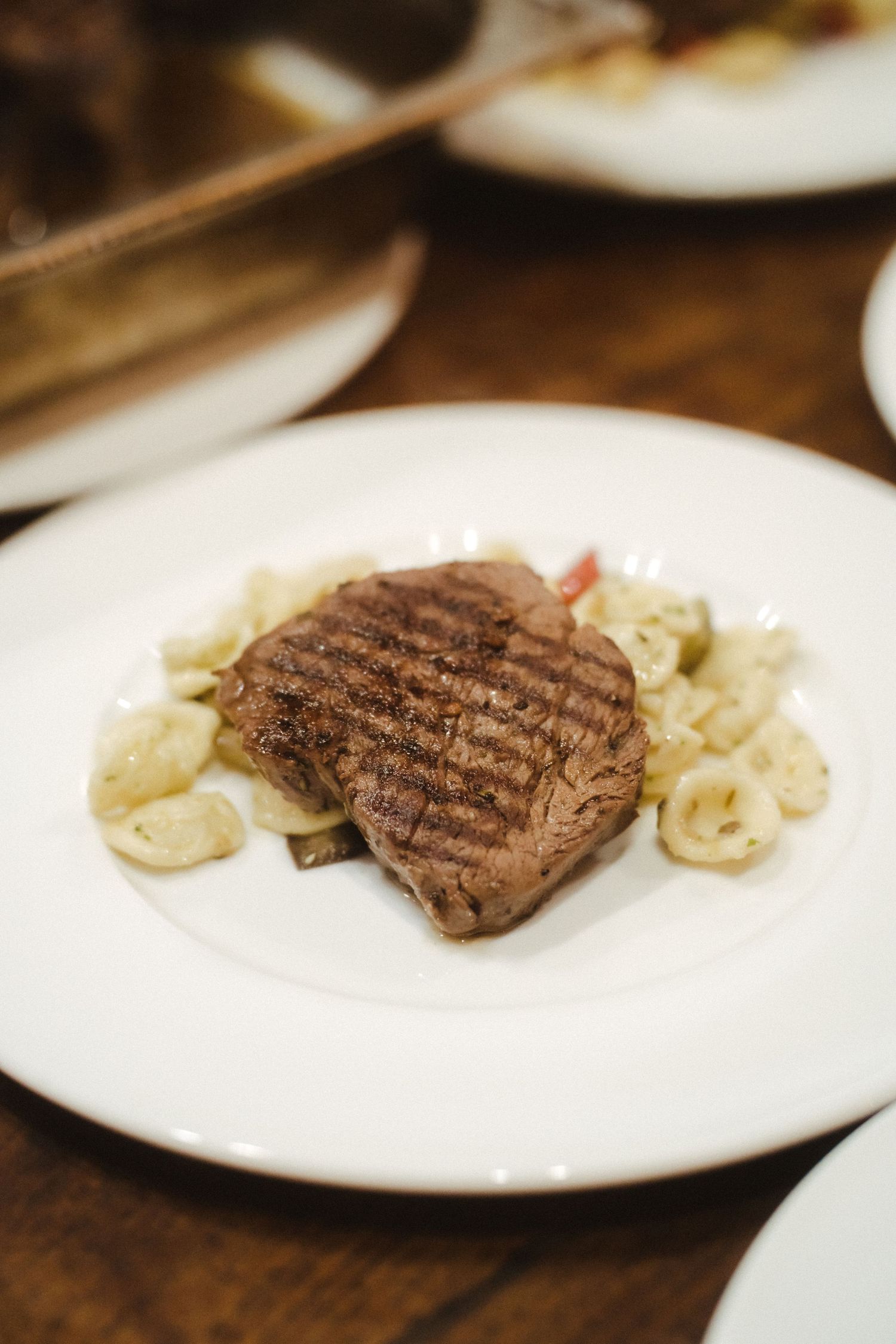Grilled steak and cauliflower served on white plates at an elegant dinner setting.
