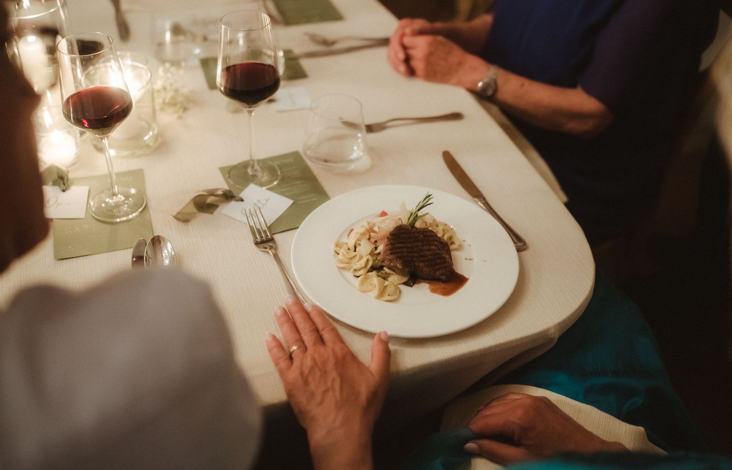 Diners enjoying wine and meals at an elegant restaurant table.