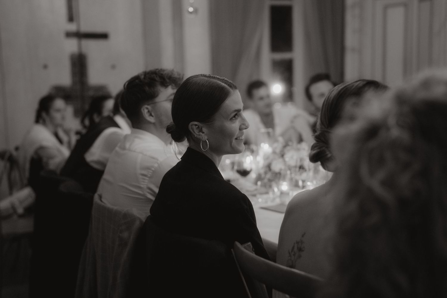 Silhouettes of dinner guests seated in a dimly lit formal dining room.