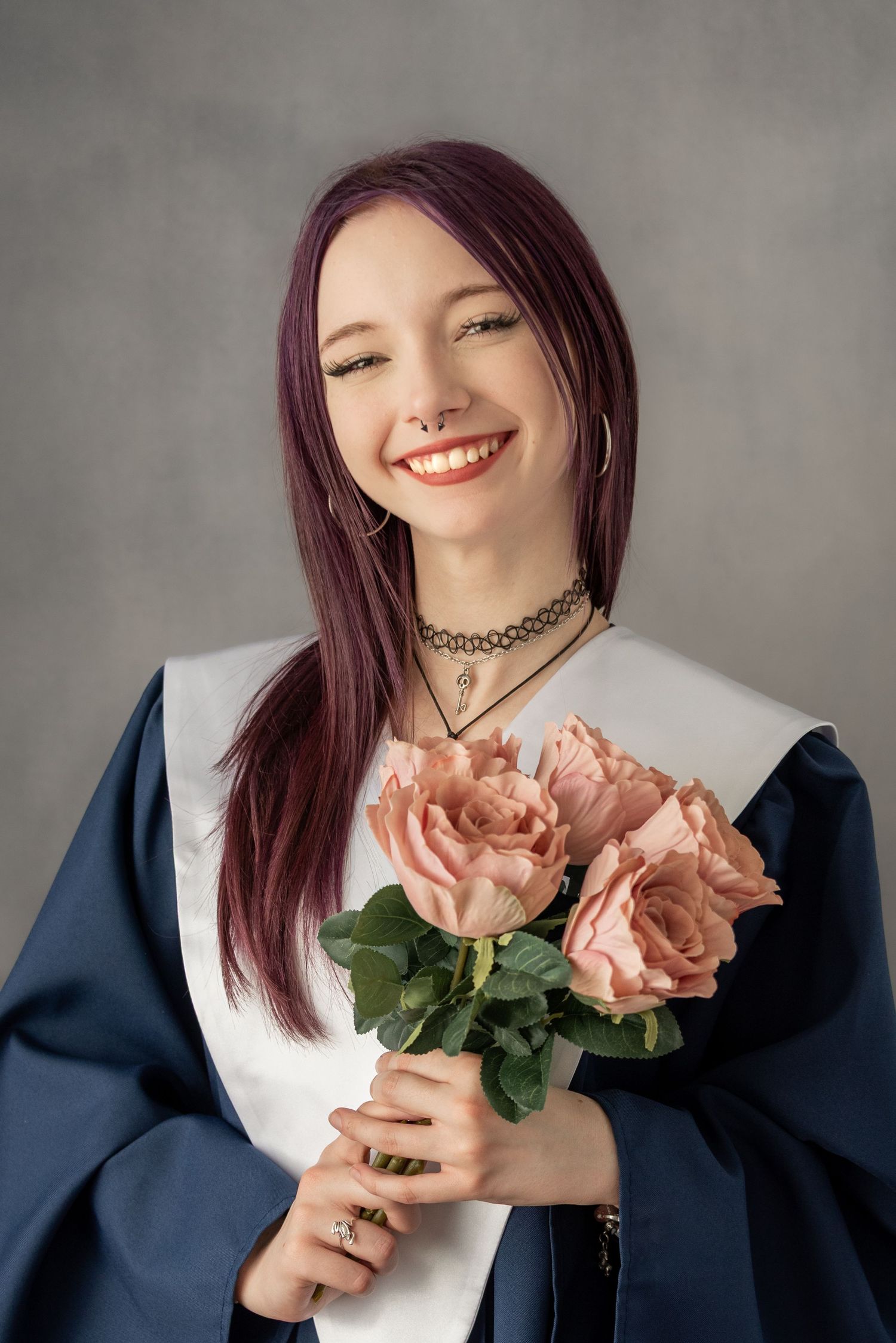 Creative portrait series with pink roses and navy outfit against grey background.