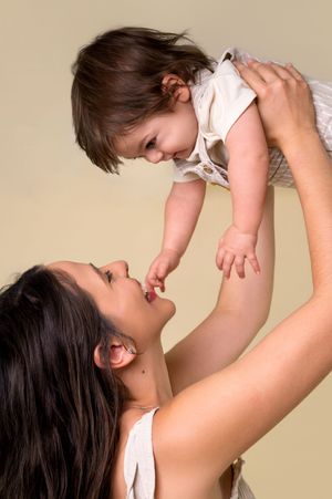 A tender moment between parent and child playing together against a neutral background.