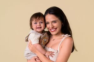 A heartwarming family portrait against a cream-colored backdrop showing joyful expressions and warm embraces.
