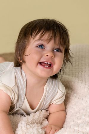 A small child with bright blue eyes lies on a white blanket in a series of candid expressions.