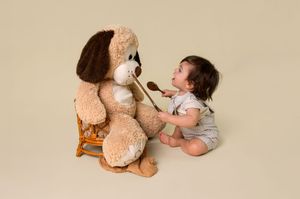 A sequence of photos showing a stuffed teddy bear and a baby interacting in playful positions on a beige background.