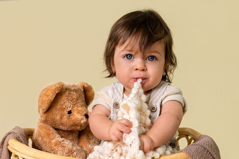 A sweet moment captured against a neutral background with a teddy bear companion.